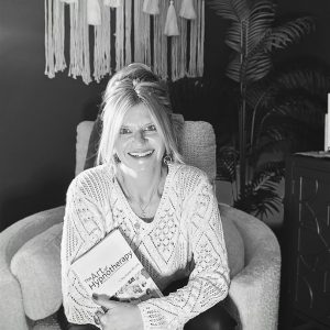 Angela holding a book in chair.