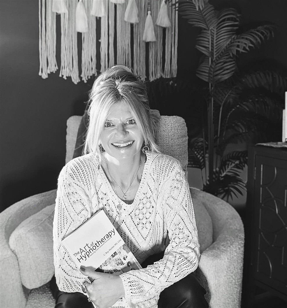 Angela holding a book in chair.